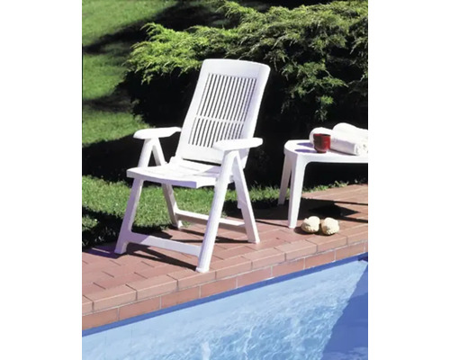 Fauteuil pliant en plastique au bord d une piscine sur une terrasse avec table d appoint assortie.
