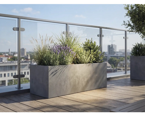Jardinière rectangulaire aspect béton sur une terrasse de toit avec plancher en bois et garde-corps en verre, plantée de lavande et de graminées.