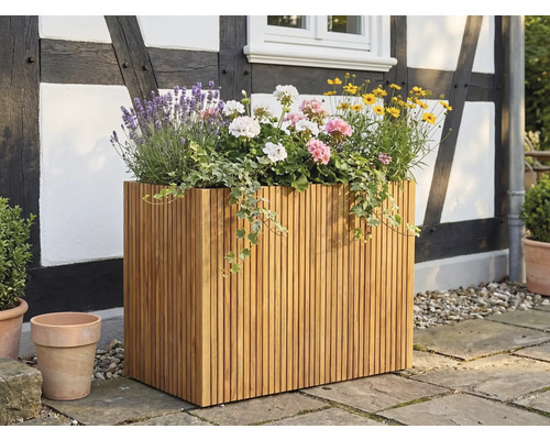 Großer rechteckiger Pflanzkübel aus Holzlatten, bepflanzt mit Lavendel und Geranien, auf einer Terrasse vor einer Fachwerkfassade.