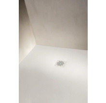 Couvercle de bonde de douche carré Laufen avec motif rayonné dans un receveur de douche texturé dans un coin de salle de bain.