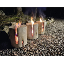 Drei brennende Schwedenfeuer aus Holz auf einem Kieselweg im Außenbereich bei Nacht mit Bäumen im Hintergrund.