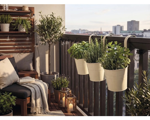 Balcon lumineux avec pots d herbes suspendus à la balustrade, meubles de salon, un petit olivier et des lanternes décoratives.