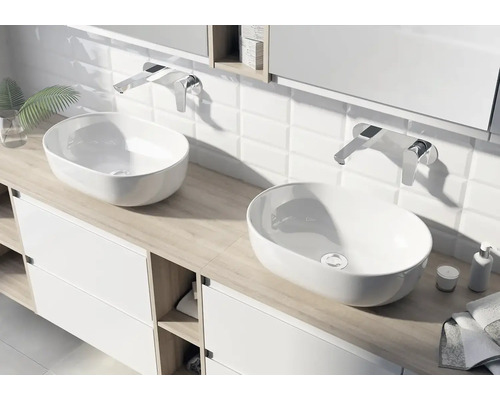 Modernes Badezimmer mit zwei ovalen Aufsatzwaschbecken aus weißer Keramik auf einem hellen Waschtischunterschrank mit Wandarmaturen.
