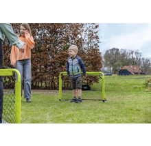 Enfants jouant avec un petit but de football portable sur une pelouse dans le jardin.