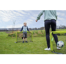 Un enfant et un adulte jouent au football dans le jardin avec deux petits buts de foot verts sur une pelouse.