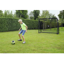 Un enfant joue au football sur une pelouse devant un but de football EXIT Toys dans un jardin.