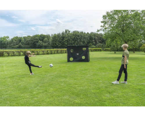 Enfants jouant au football dans un jardin avec un but de football et une paroi de tir sur une pelouse.