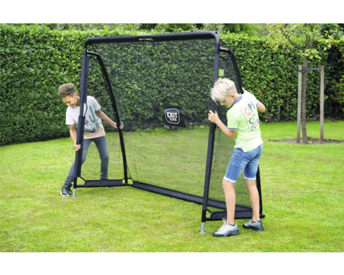 Deux garçons jouent dans le jardin avec un filet de rebond EXIT Toys sur une pelouse devant une haie.