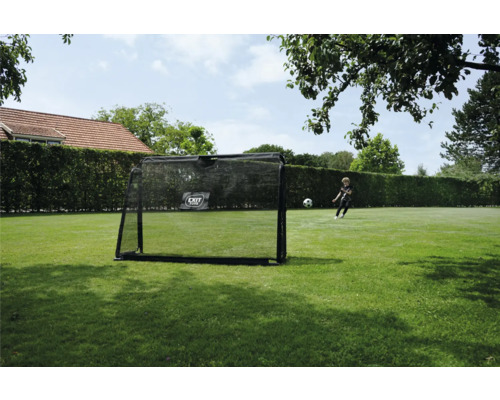 But de football EXIT Toys sur une pelouse dans un jardin avec un enfant tirant dans un ballon de foot.