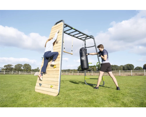 Station de fitness extérieure EXIT Toys GetSet en métal et bois avec mur d escalade, sac de frappe et espalier dans un jardin.