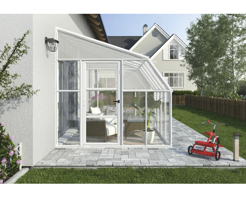 Moderner Anlehn-Wintergarten aus weißem Aluminium und Glas, an eine Hauswand montiert, auf einer gepflasterten Terrasse mit Gartenmöbeln.