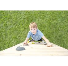 Un enfant grimpe sur un mur d escalade en bois avec des prises colorées sur une pelouse.