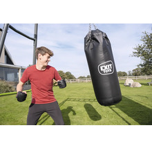 Un jeune homme avec des gants de boxe dans un jardin à côté d'un sac de frappe noir EXIT TOYS suspendu à un cadre métallique sur une pelouse.