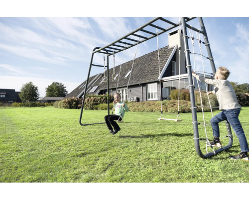 Enfants jouant sur un grand portique d escalade en métal dans un jardin avec balançoire, anneaux, filet de grimpe et barre de singe.