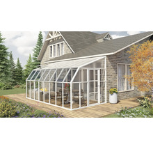 Moderner weißer Wintergarten aus Aluminium und Glas an einer Backsteinwand auf einer Holzterrasse mit Gartenmöbeln im hellen Außenbereich.