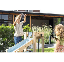 Enfants jouant avec un circuit d eau en bois dans le jardin. Un garçon verse de l eau d un verre doseur dans la rigole supérieure.