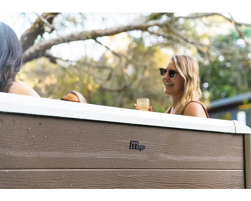 Vue extérieure d'un jacuzzi MSpa avec panneaux aspect bois et personnes dans un jardin.