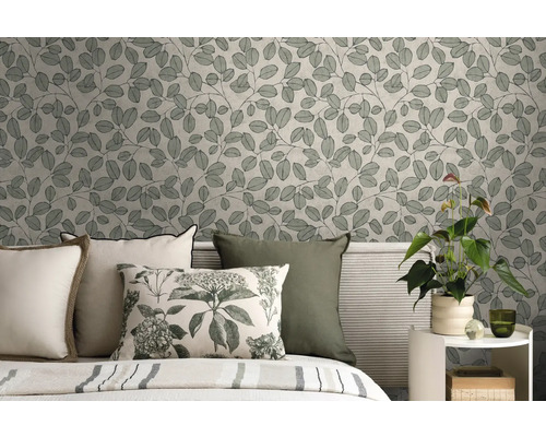 Vliestapete mit botanischem Blättermuster im Schlafzimmer hinter einem Bett mit Kissen und einer Zimmerpflanze auf einem Beistelltisch.