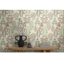 Vliestapete mit botanischem Blatt- und Blumenmuster in gedeckten Farben an einer Wand hinter einem Holztisch mit dekorativen Vasen.