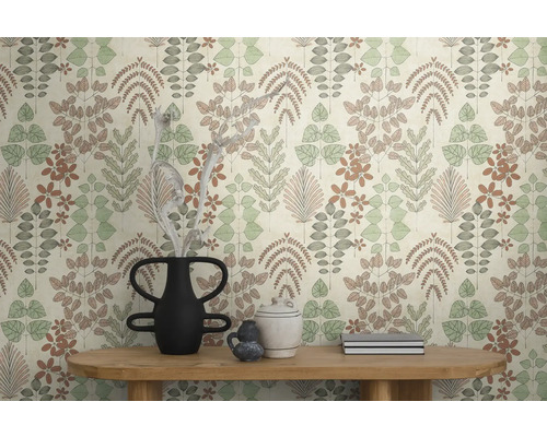 Vliestapete mit botanischem Blatt- und Blumenmuster in gedeckten Farben an einer Wand hinter einem Holztisch mit dekorativen Vasen.