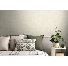 Schlafzimmer mit hell strukturierter Tapete, Dekokissen mit Blumenmuster und Beistelltisch mit Zimmerpflanze.