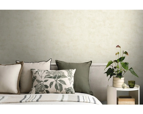 Schlafzimmer mit hell strukturierter Tapete, Dekokissen mit Blumenmuster und Beistelltisch mit Zimmerpflanze.