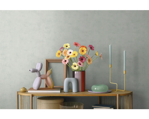 Décoration de buffet moderne avec des gerberas colorés dans un vase, une sculpture de chien ballon, un cadre en bois et des bougeoirs.