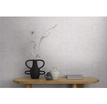 Hellgraue strukturierte Tapete in Betonoptik an einer Wand in einem minimalistischen Raum mit Holztisch und Dekoration.