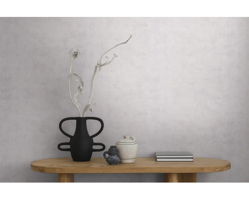 Hellgraue strukturierte Tapete in Betonoptik an einer Wand in einem minimalistischen Raum mit Holztisch und Dekoration.