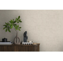 Papier peint intissé aspect crépi sur un mur derrière un buffet en bois avec une décoration comprenant un vase avec des branches et une sculpture.