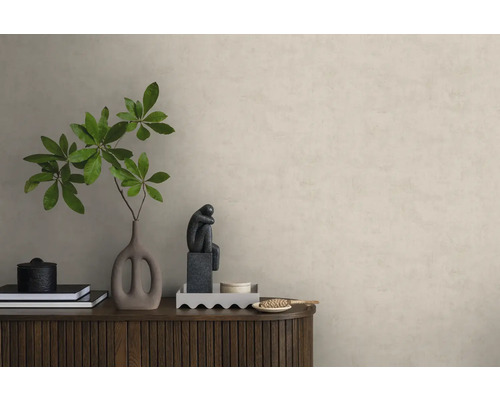 Papier peint intissé aspect crépi sur un mur derrière un buffet en bois avec une décoration comprenant un vase avec des branches et une sculpture.