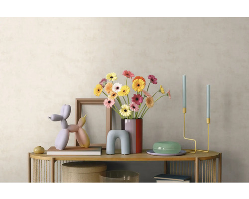 Intérieur moderne avec buffet en bois, bouquet de gerberas, sculpture de chien ballon, chandeliers et cadre photo devant un mur clair.