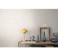 Agencement lumineux et organisé sur un buffet en bois devant un mur clair texturé avec une lampe de table jaune, une horloge et un vase à fleurs.