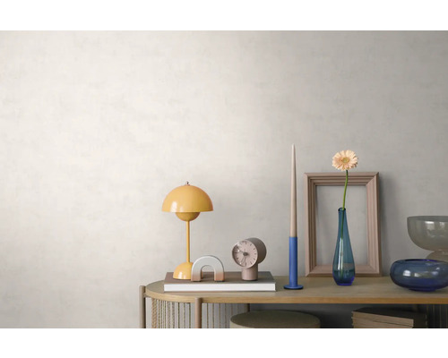 Agencement lumineux et organisé sur un buffet en bois devant un mur clair texturé avec une lampe de table jaune, une horloge et un vase à fleurs.