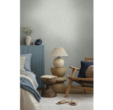 Chambre moderne avec papier peint texturé, meubles en bois, panneaux muraux bleus, lampe décorative et textiles dans une atmosphère lumineuse.