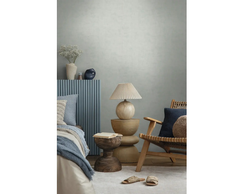 Chambre moderne avec papier peint texturé, meubles en bois, panneaux muraux bleus, lampe décorative et textiles dans une atmosphère lumineuse.