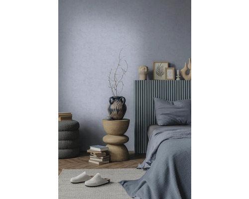 Chambre moderne avec mur bleu clair texturé, lit avec tête de lit à lattes grises et table d'appoint sculpturale en bois.