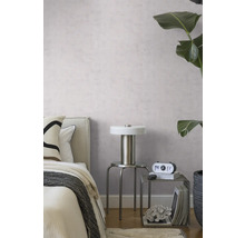 Modernes Schlafzimmer mit hellvioletter Strukturtapete, Metalllampe auf einem Hocker und einer großen grünen Zimmerpflanze.