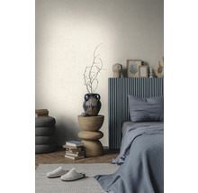Mur clair texturé dans une chambre minimaliste avec un lit gris, une table d'appoint en bois et un parquet en chevrons.