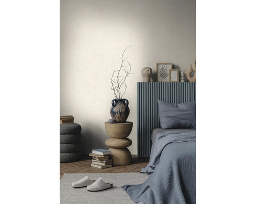 Mur clair texturé dans une chambre minimaliste avec un lit gris, une table d'appoint en bois et un parquet en chevrons.