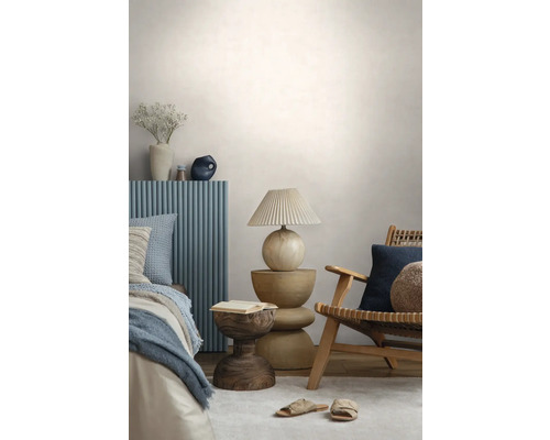 Chambre à coucher moderne avec un fauteuil en bois, une table de chevet sculpturale, une lampe avec abat-jour plissé et un lit avec panneau bleu.