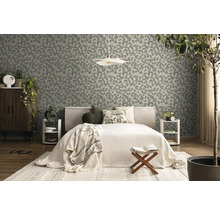 Vliestapete mit Blattmuster in einem hellen Schlafzimmer mit Bett, Holzmöbeln und Zimmerpflanzen.