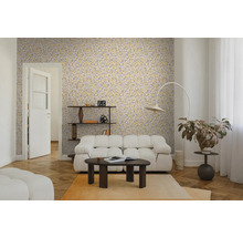 Salon avec papier peint jaune à motifs de feuilles, canapé blanc, table basse foncée et parquet. Ambiance lumineuse et moderne.