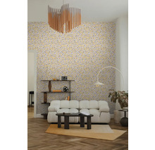 Salon clair et organisé avec papier peint à motif de feuilles, canapé modulable blanc, table basse foncée, lampadaire arqué et étagère en bois.