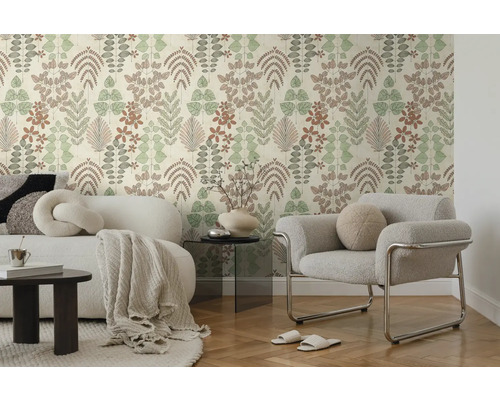Modernes Wohnzimmer mit Vliestapete im Blättermuster, weißem Sofa mit Decke und grauem Sessel auf Parkettboden.