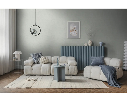 Salon moderne lumineux avec canapé modulaire blanc, buffet bleu, mur gris, tapis clair et table d'appoint ronde.