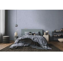 Chambre à coucher moderne avec mur texturé bleu-gris, lit à tête de lit nervurée, parquet et tapis foncé.