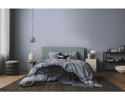 Chambre à coucher moderne avec mur texturé bleu-gris, lit à tête de lit nervurée, parquet et tapis foncé.