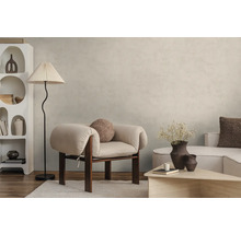 Salon moderne avec peinture murale beige clair effet béton, fauteuil clair, lampadaire et étagère blanche sur parquet.