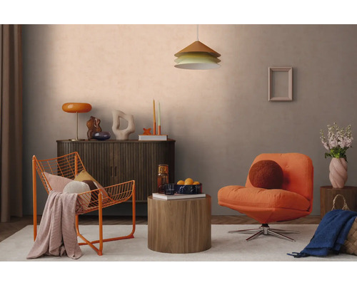 Modern agericht Wunnzëmmer mat orangefarbenem Drahtsessel, Polstersessel, donkelem Sideboard a ronnem Holzbeistelltisch virun enger hellgroer Mauer.